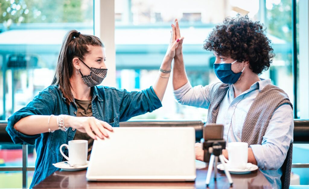 Young milenial influencers at coworking space with facemask