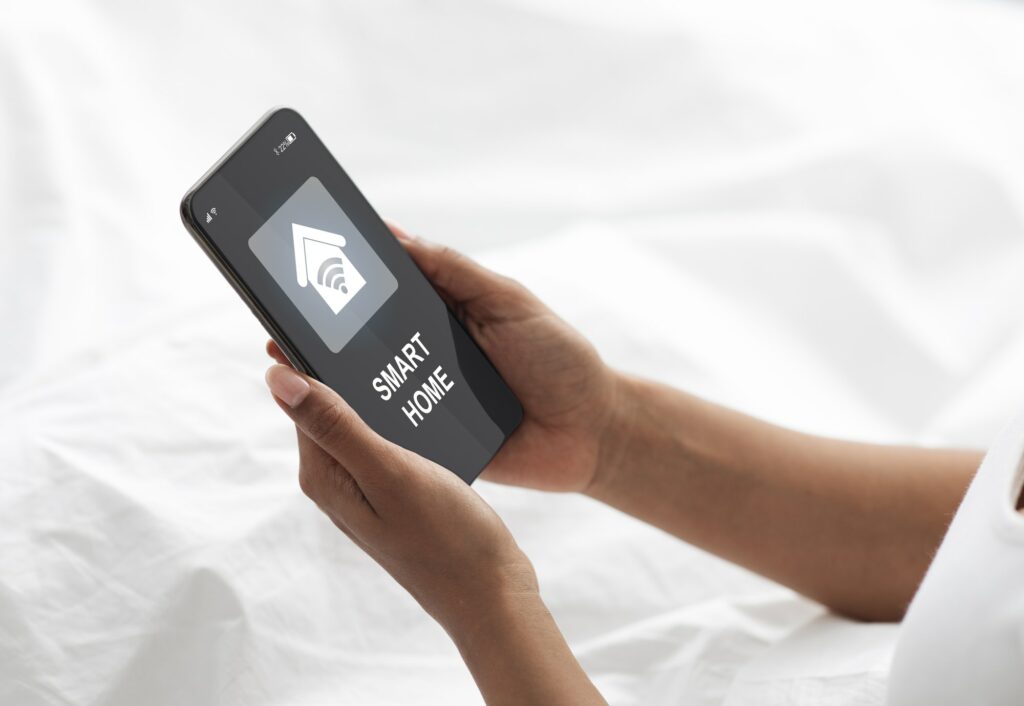Woman laying in bed, using smart home app on smartphone