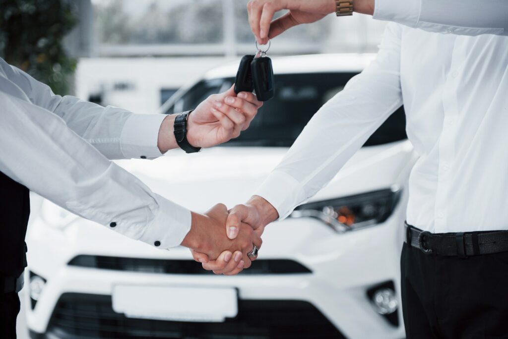 Close up of sales manager in black suit selling the car to the customer